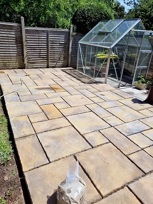 New sandstone patio laid around the greenhouse